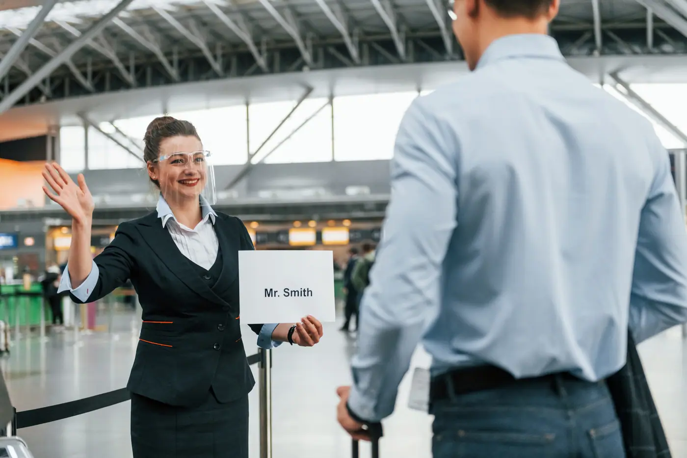 Meet-and-greet host with a name sign welcoming a traveller at the airport